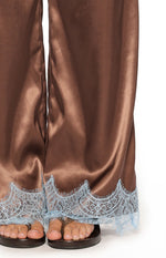 Close-up of the light blue scalloped lace trim at the hem of the brown satin wide-leg pants