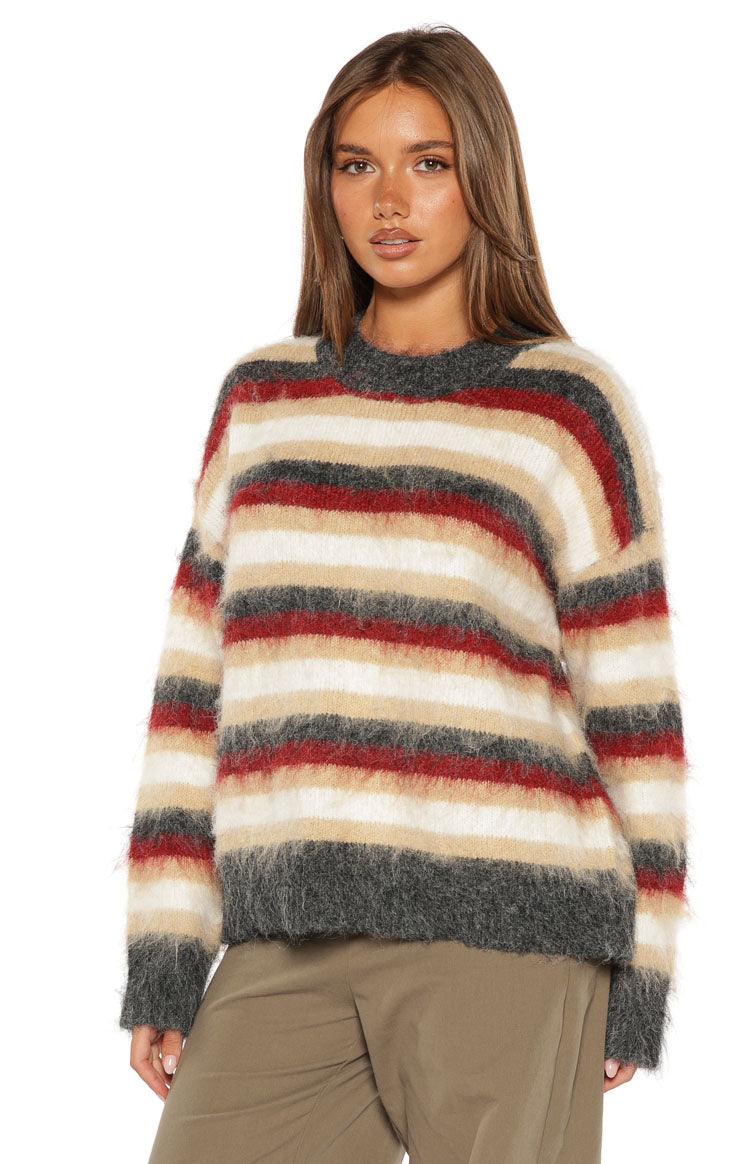 Close-up front view of a fuzzy multi-stripe oversized sweater with crew neck in white, beige, red, and dark grey