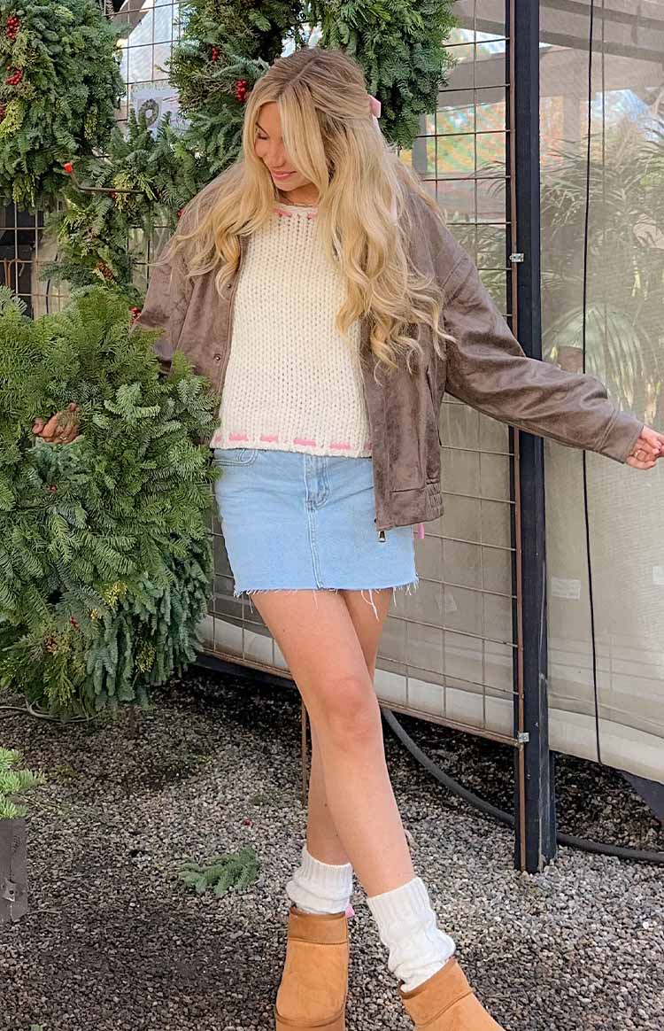 Front view of a light wash denim mini skirt featuring a low rise waist and frayed hem