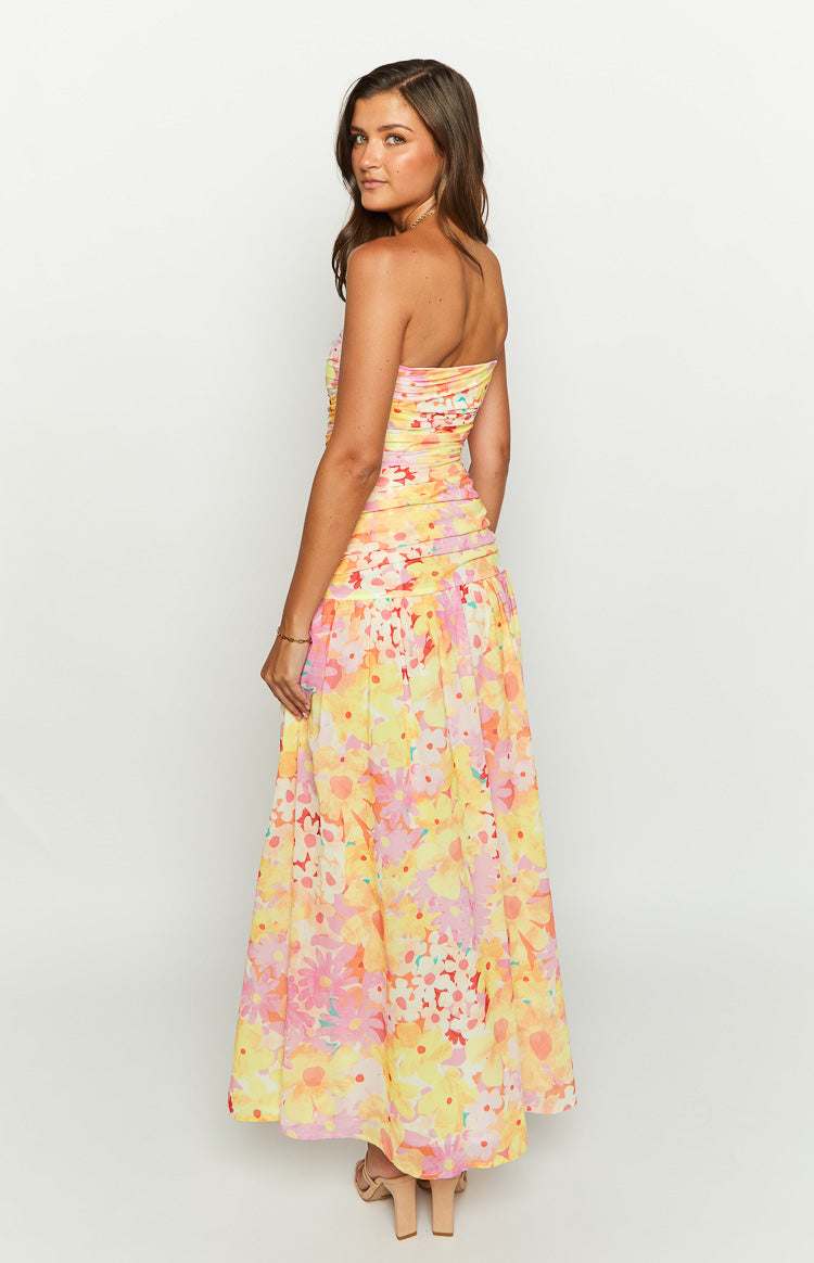 Side view of a yellow floral print strapless maxi dress with a ruched bodice and flowy skirt