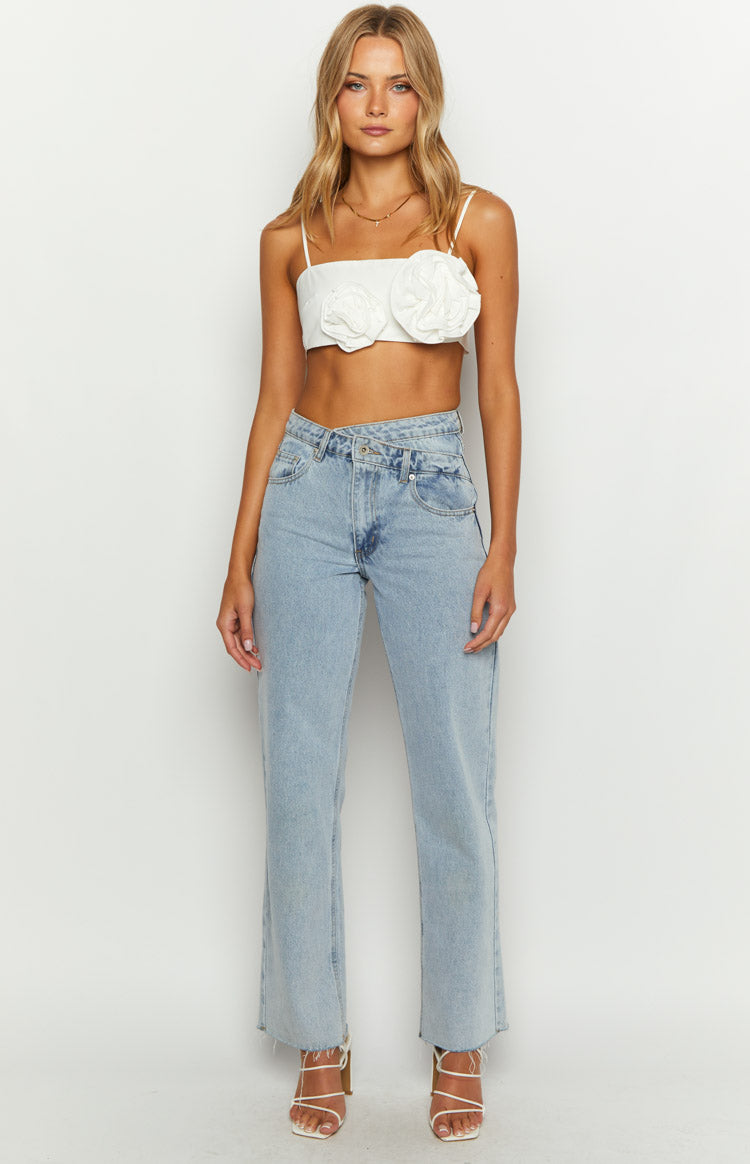 Front view of a white crop top with two textured rose appliques and thin spaghetti straps