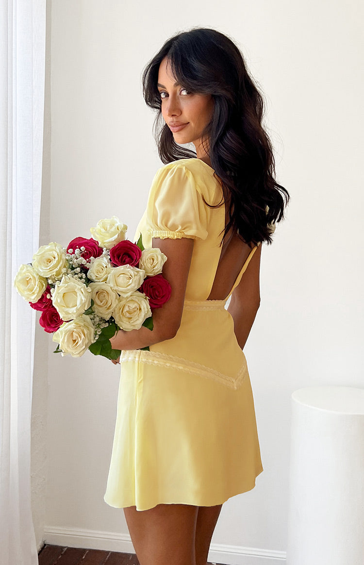 Rear view showing the low scoop back, thin straps, and lace trim detail on the yellow mini dress