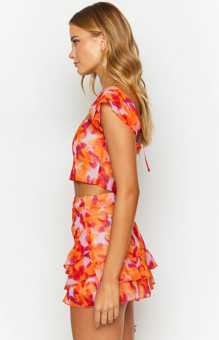 Side view of an azalea pink print crop top with flutter short sleeves and a side tie detail