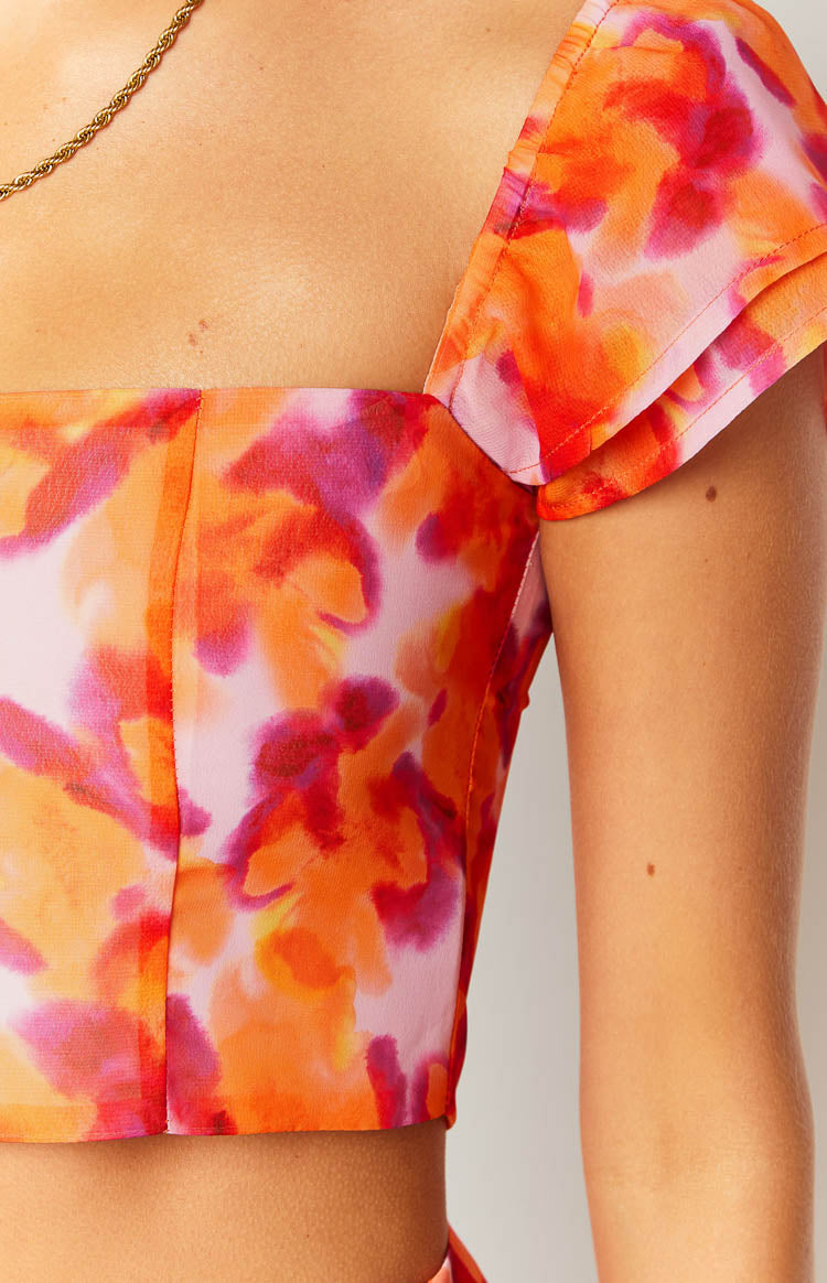 Detail of the azalea pink print crop top showing the square neckline, side seam, and layered flutter sleeve