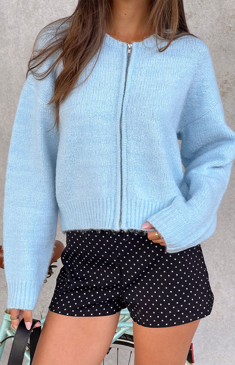 Close-up of the light blue knit cardigan with a visible fluffy texture, silver front zipper, and ribbed cuffs and hem