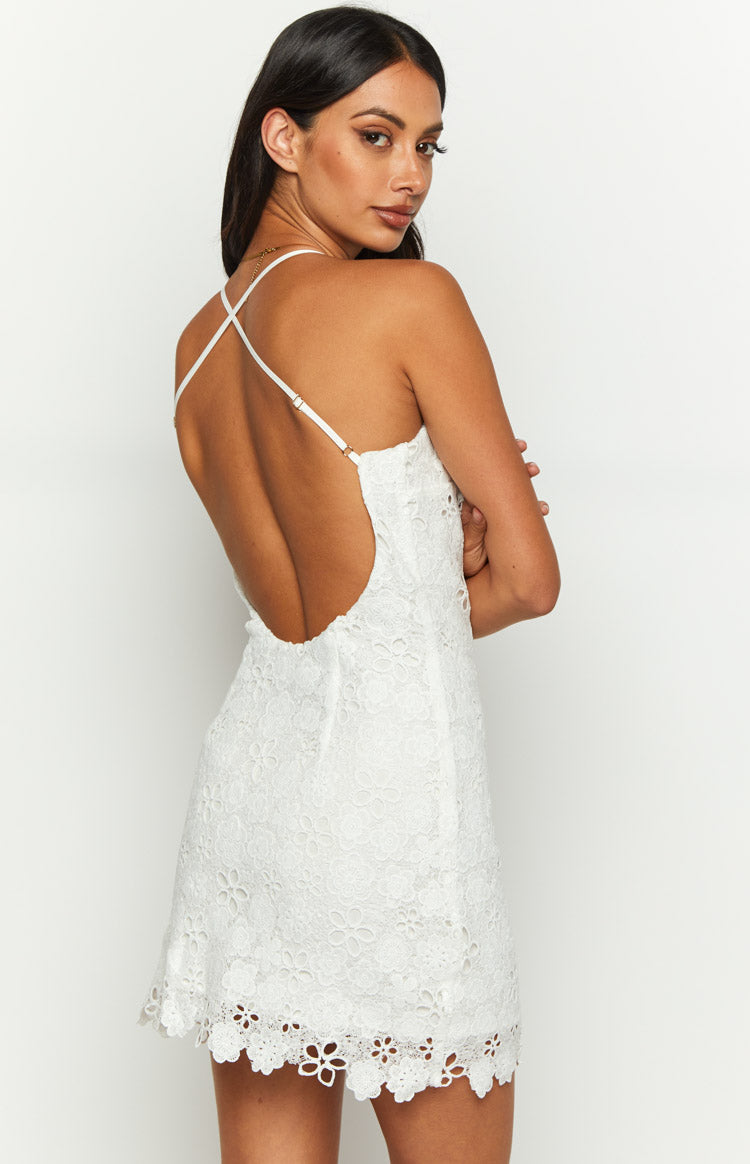 Rear view of a white lace mini dress showing the low scoop back, criss-cross spaghetti straps, and scalloped hem