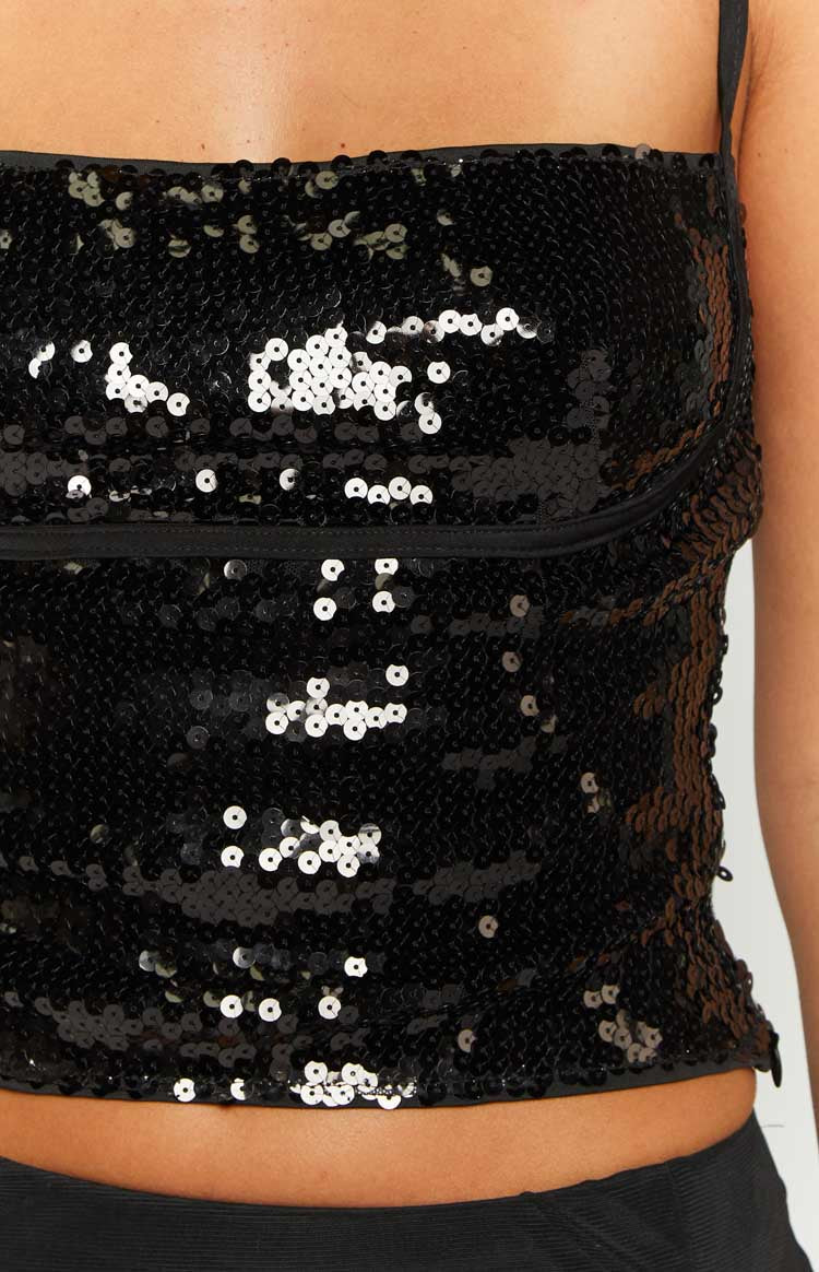 Close-up of the black sequin fabric and horizontal bust seam detail on a fitted top