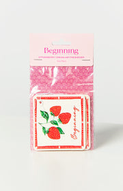 Two white air fresheners with red strawberry illustrations, red dotted border, and 'Beginning' script, in clear plastic packaging