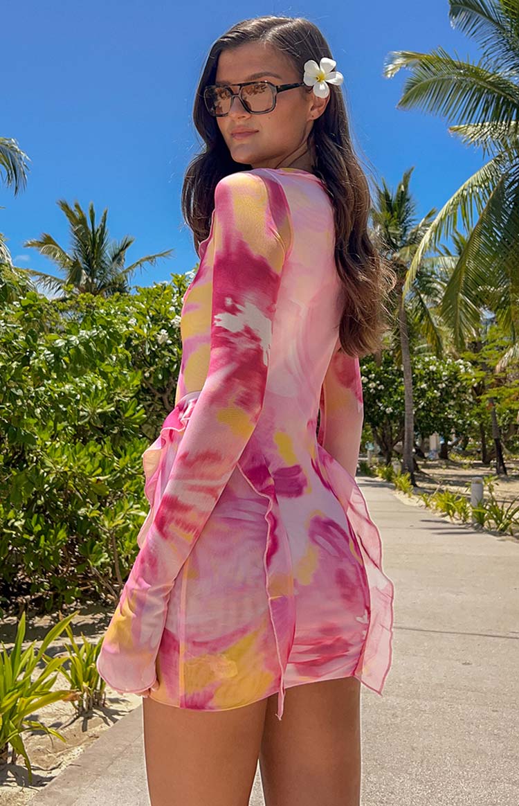 Side view of the sheer pink and yellow tie-dye mesh mini dress with long sleeves and ruffled hem