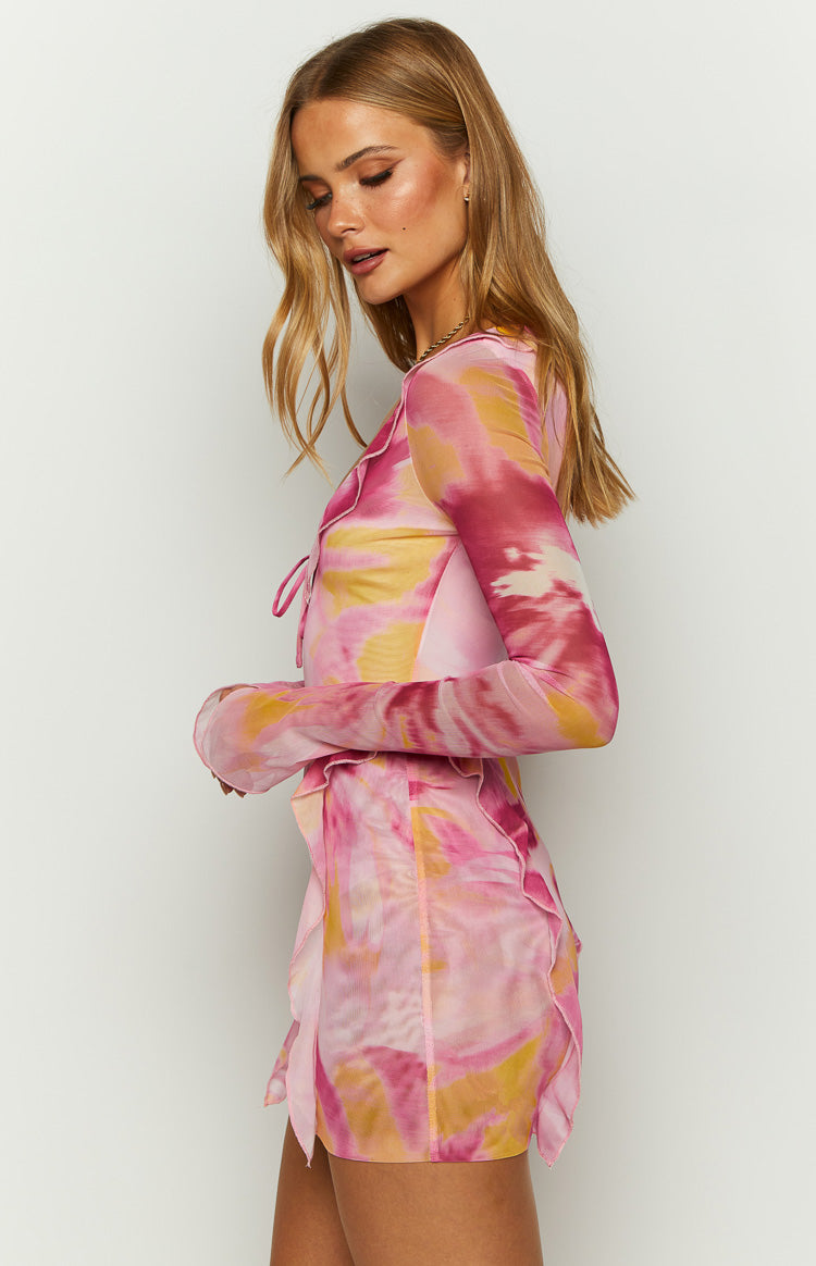 Side view of a pink and yellow floral mesh long sleeve mini dress with a tie-front bodice and ruffled hem