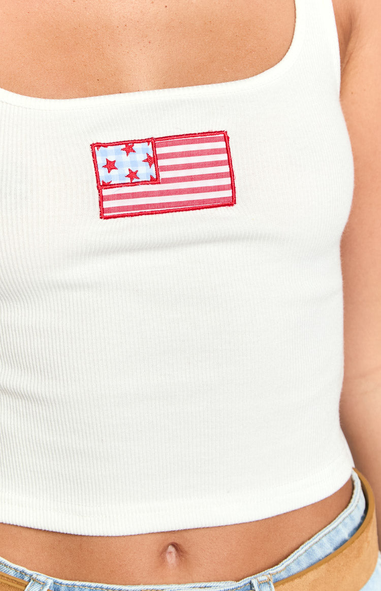 Close-up of the embroidered USA flag patch on a white ribbed tank top with red and blue details