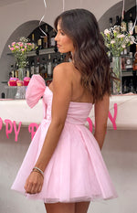 Side view of a pink strapless mini dress with a large bow detail on the bodice and a full tulle skirt