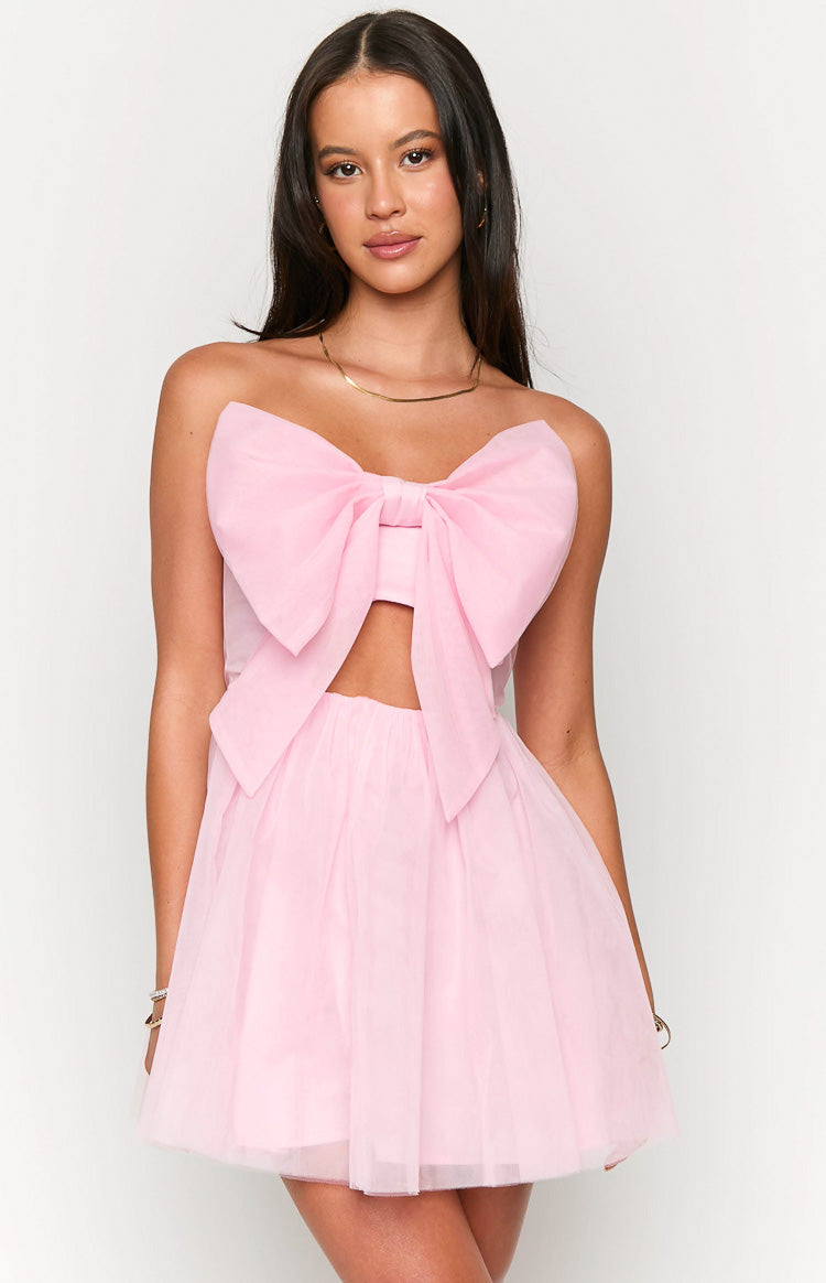 Front view of a light pink strapless mini dress with a large bow detail on the bust and a cutout under the bust