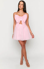 Front view of a light pink strapless mini dress with a large bow detail on the bust and a cutout waist