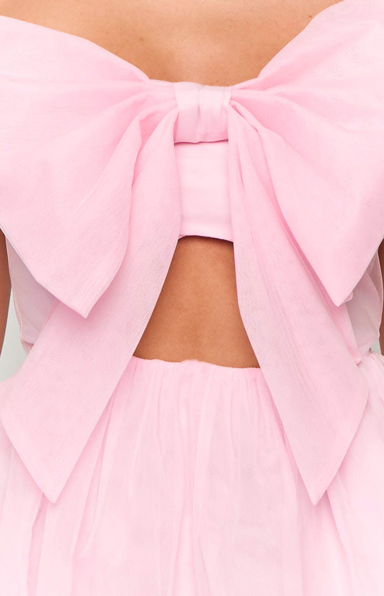 Close-up of the back of a pink mini dress showing a large sheer bow, a cutout detail, and the top of the tulle skirt