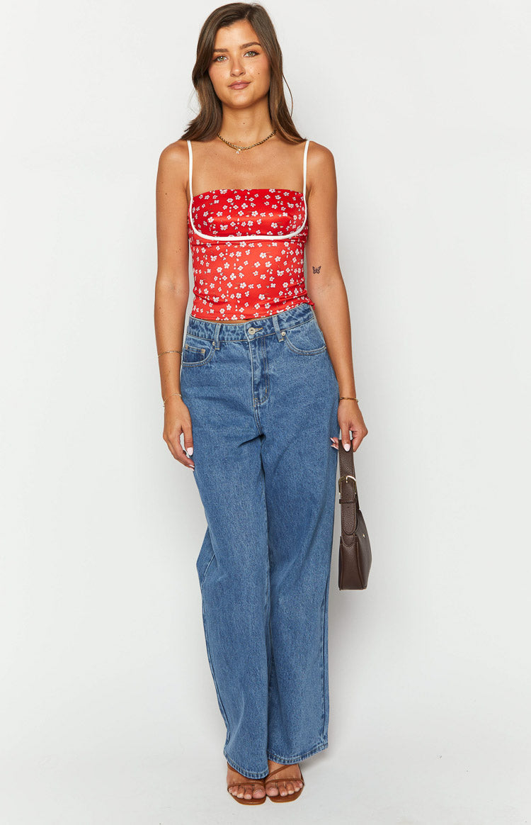 Front view of a red floral fitted top with white spaghetti straps and white bust trim