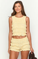 model wearing yellow gingham shorts with ruched and ruffle details and a yellow gingham ruched sleeveless top 