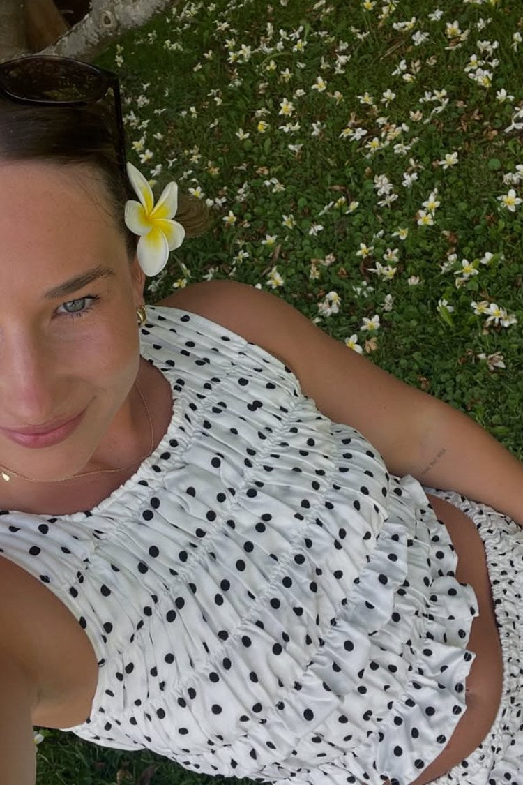 Close-up of a white polka dot top with extensive ruching and a sleeveless design