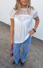 White sheer mini dress with high lace neck, lace yoke, and short puff sleeves
