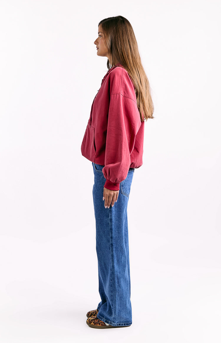 Side view of a washed red oversized hooded jacket with dropped shoulders and ribbed cuffs