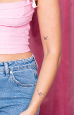 Small butterfly semi-permanent tattoo on the upper arm and a scorpion tattoo on the forearm