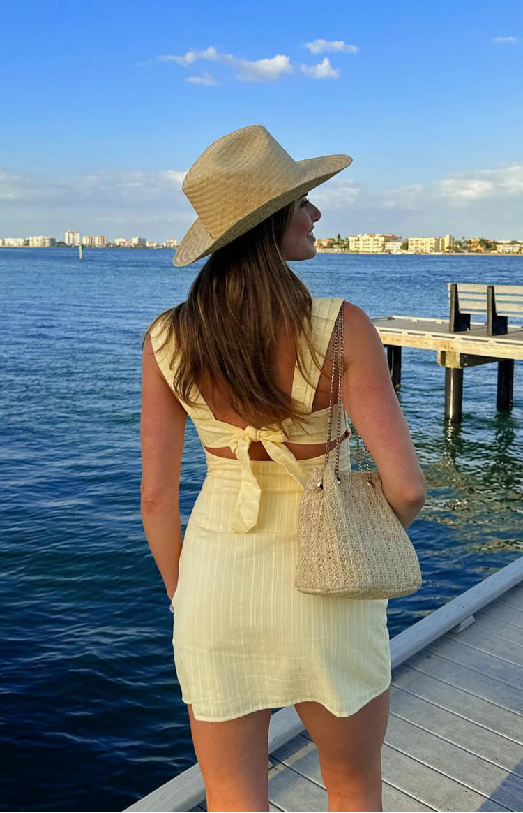 Rear view of a yellow striped mini dress with a tie-back detail and waist cutouts