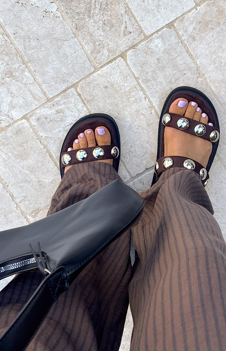 Top-down view of chocolate suede platform sandals with two wide straps adorned with silver studs