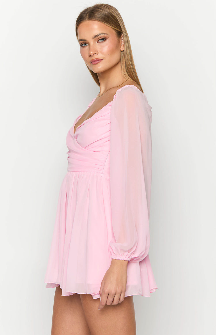 Side view of a pink mini dress showing the ruched bodice and sheer long sleeves with elasticated cuffs