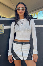 Front view of a white and black contrast PU low waist mini skirt with a silver front zip