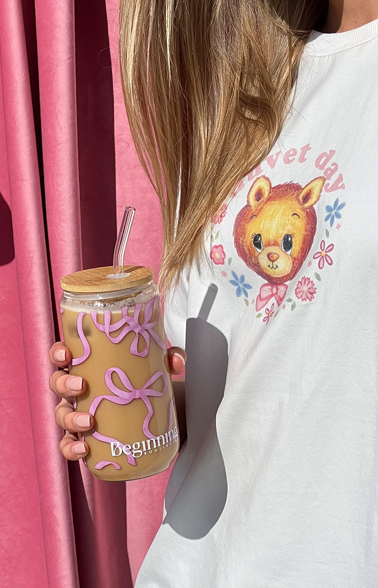 Clear glass tumbler with a repeating pink bow pattern, natural bamboo lid, and bent glass straw