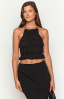 blonde model wearing a black halter neck top with gathered ruched details paired with a matching black skirt