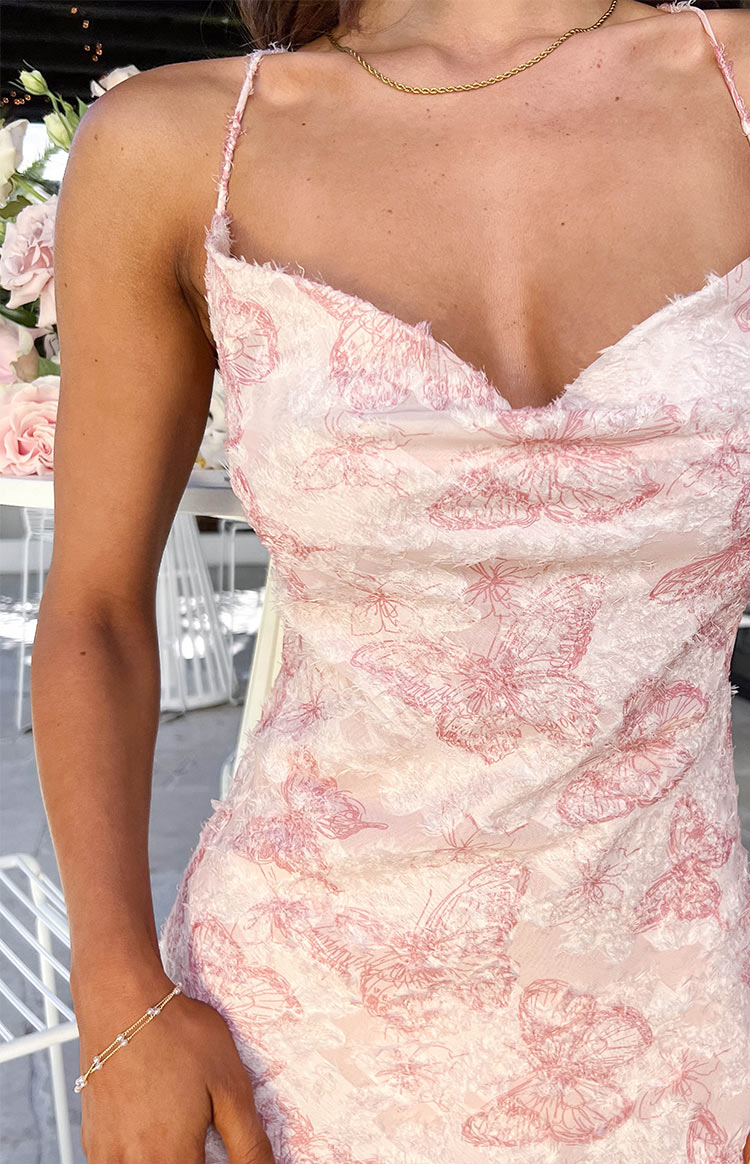 Close-up of the pink butterfly pattern on the textured fabric with a frayed cowl neckline of a maxi dress
