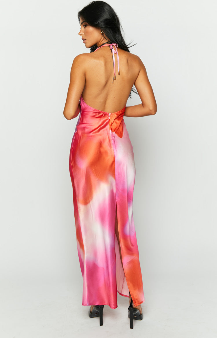 Rear view of a pink, orange, and white abstract print satin maxi dress with an open back, halter neck ties, and a high leg split