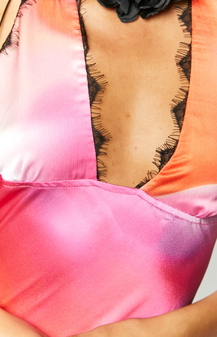 Close-up of the pink and orange gradient satin maxi dress bust with black lace trim and a black floral halter neck detail