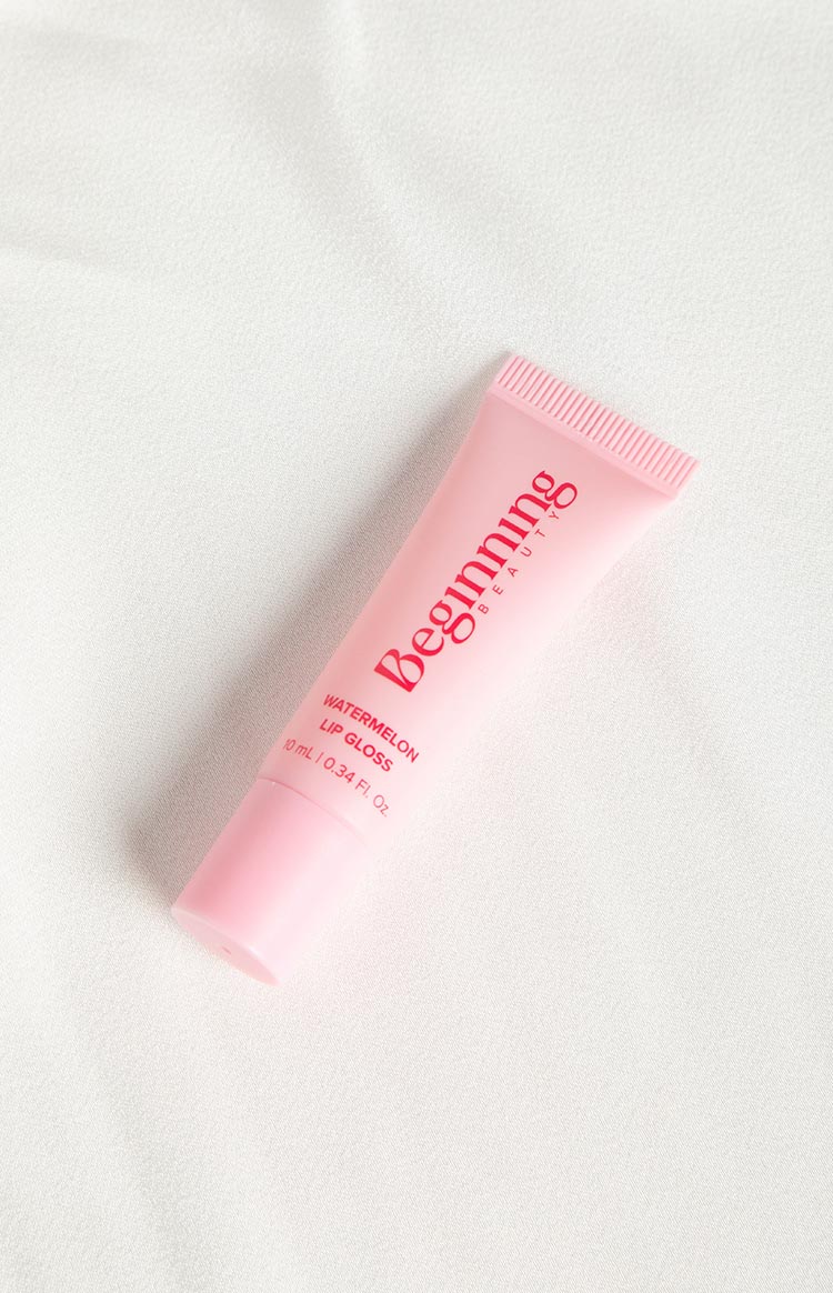 Angled view of a light pink lip gloss tube with 'WATERMELON LIP GLOSS' and '10 mL' text
