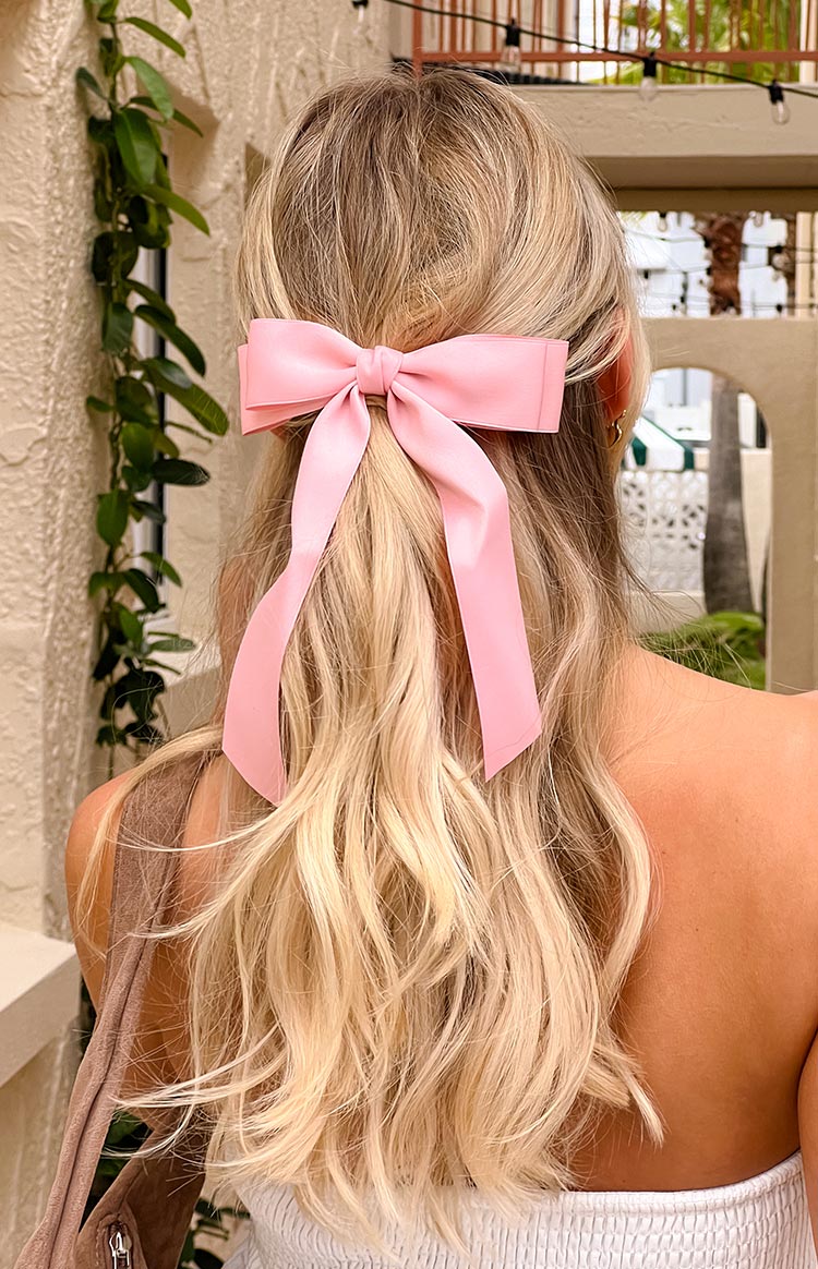 Rear view of a soft pink satin bow hair clip with long flowing ribbon tails