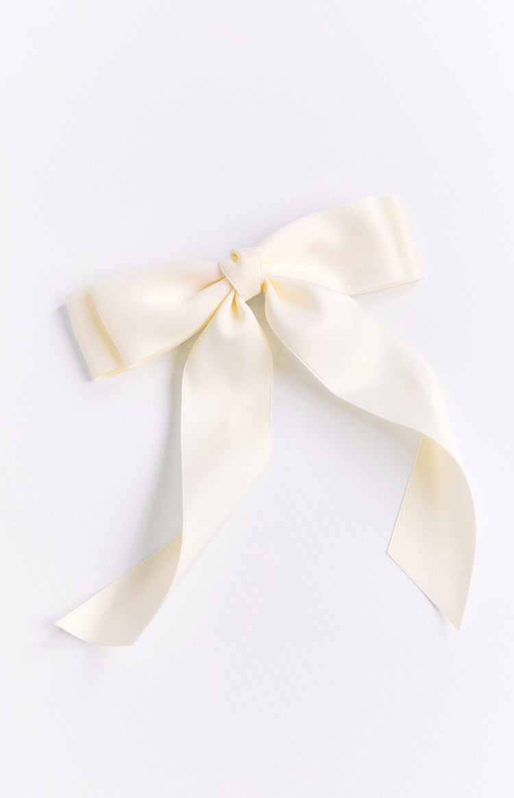 Cream satin ribbon bow hair clip with a central knot and long flowing tails, showing the fabric's sheen