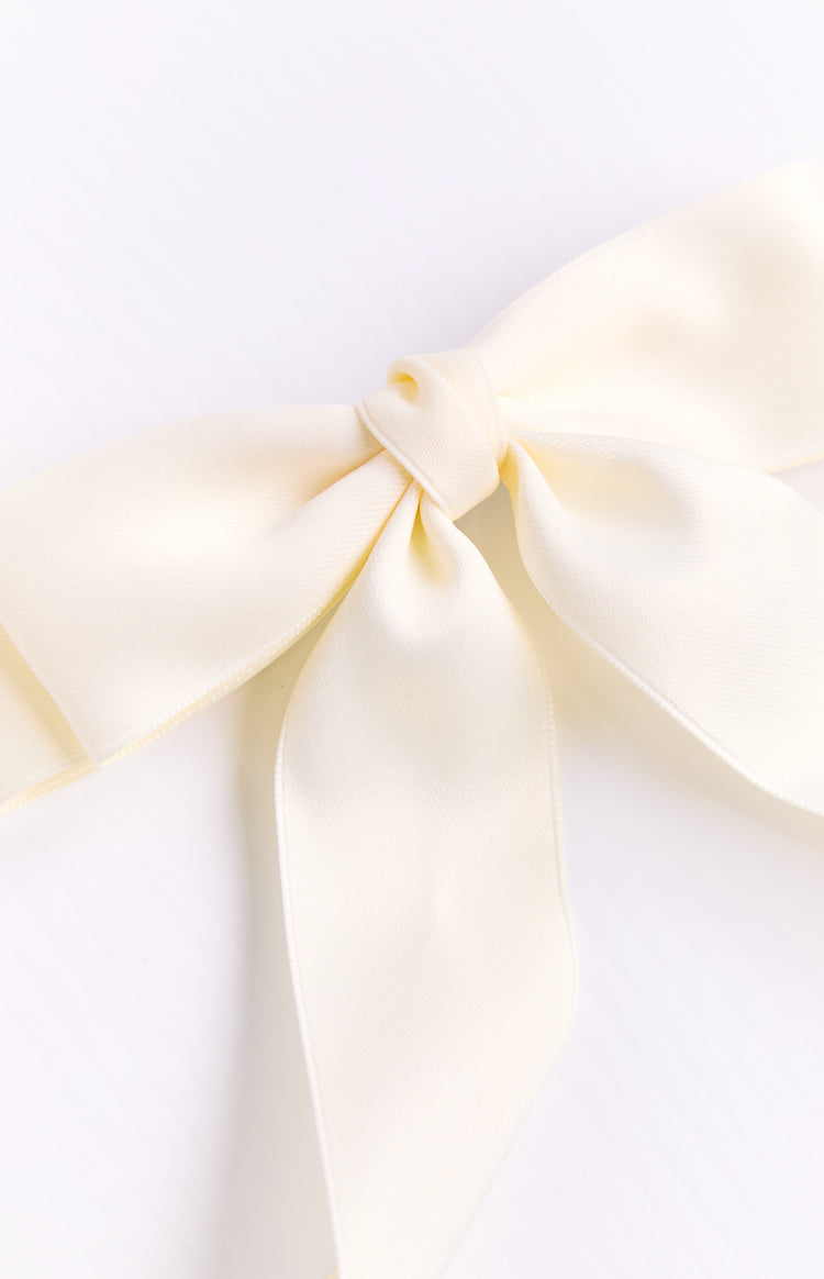 Close-up of a cream satin bow showing the central knot and smooth fabric texture