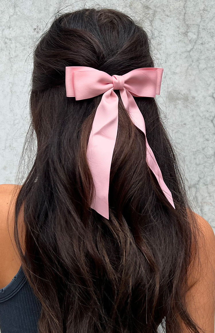 Close-up of a pink satin bow hair clip with long flowing tails