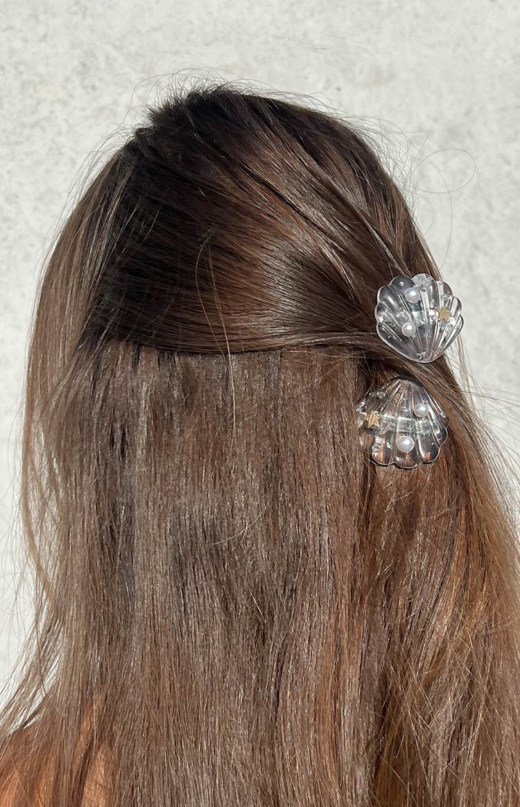 Detail shot of two clear shell hair clips featuring small white pearls and tiny gold stars