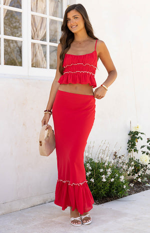 Model styles the Wiatt Red Maxi Skirt with a white top a versatile and flowy skirt perfect for a summer vacation or a casual day out.