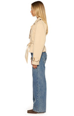 Side view of a cream cropped trench coat with a tied waist belt and buckled cuff straps
