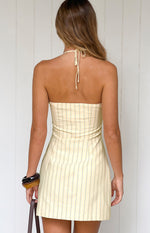 Rear view of a yellow stripe halter neck mini dress with a tied back neck and vertical stripes