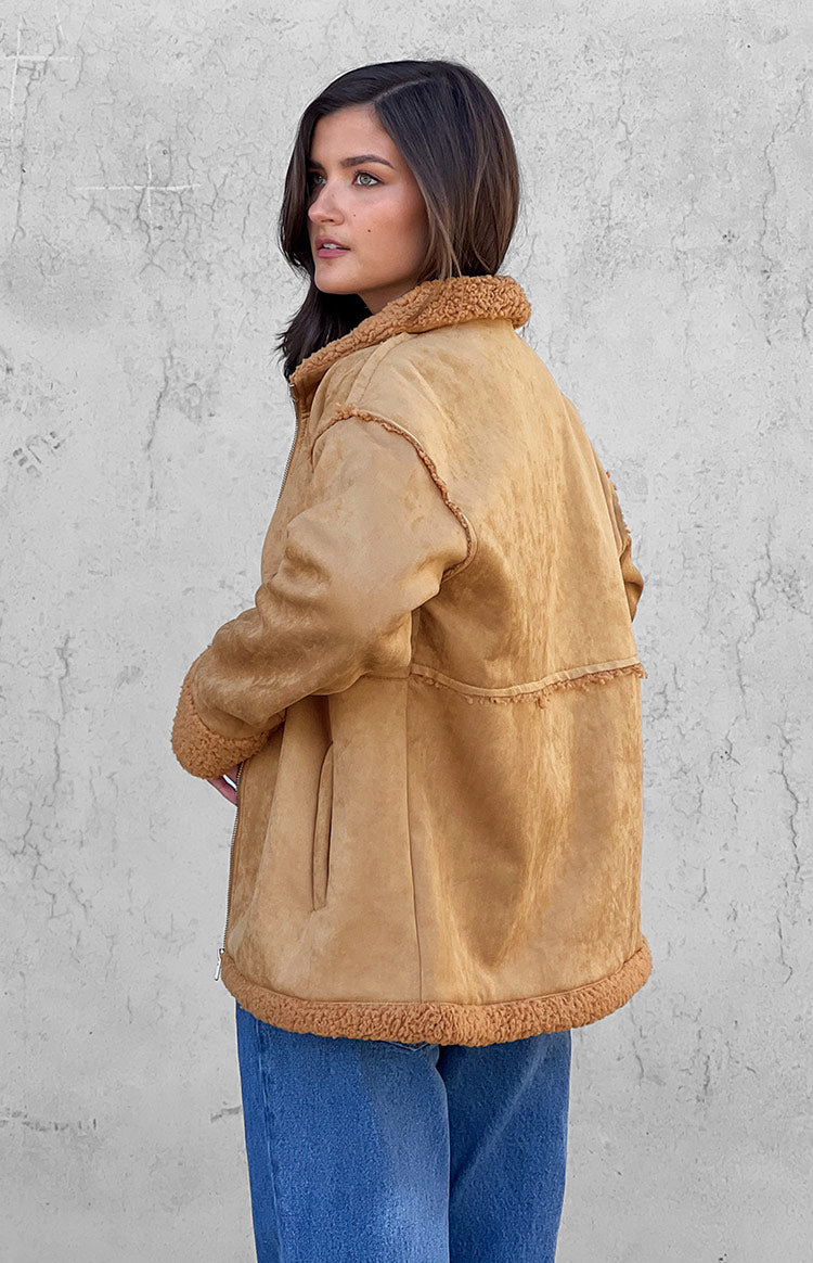 Side view of an oversized brown suede jacket with exposed fur seams and fur trim on collar and hem