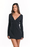 A black mini-dress adorned with a white polka dot pattern- featuring a deep V-neckline and long- slightly flared sleeves.
