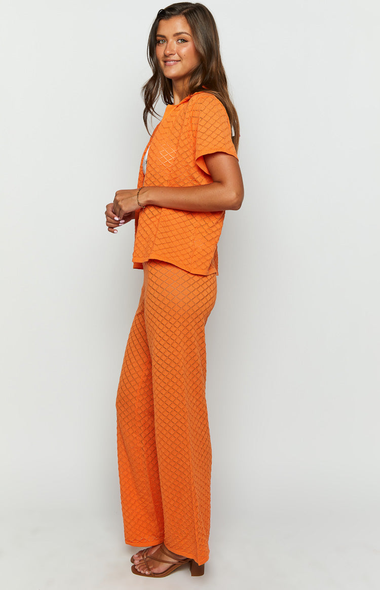 Side view of orange wide-leg knit pants with a diamond open-knit pattern