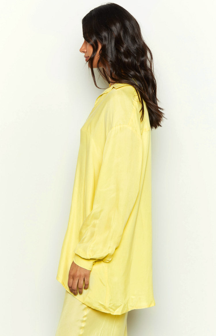 Side view of a yellow cupro button-up shirt with long sleeves and a relaxed fit