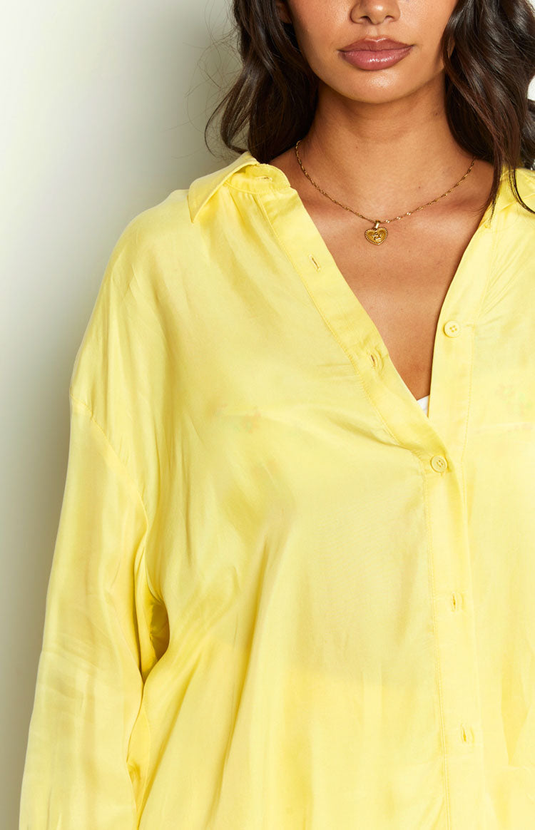 Close-up of the soft, slightly sheer yellow cupro fabric and open button-up neckline of the shirt