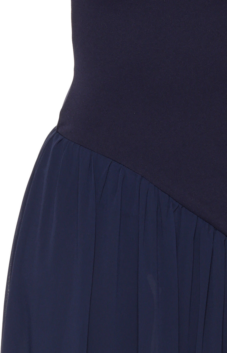 Close-up of the navy maxi dress showing the diagonal seam where the fitted bodice joins the gathered skirt