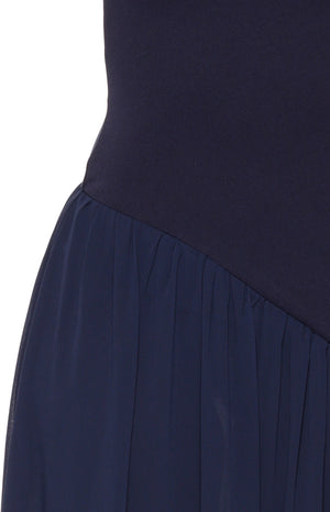 Close-up of the navy maxi dress showing the diagonal seam where the fitted bodice joins the gathered skirt